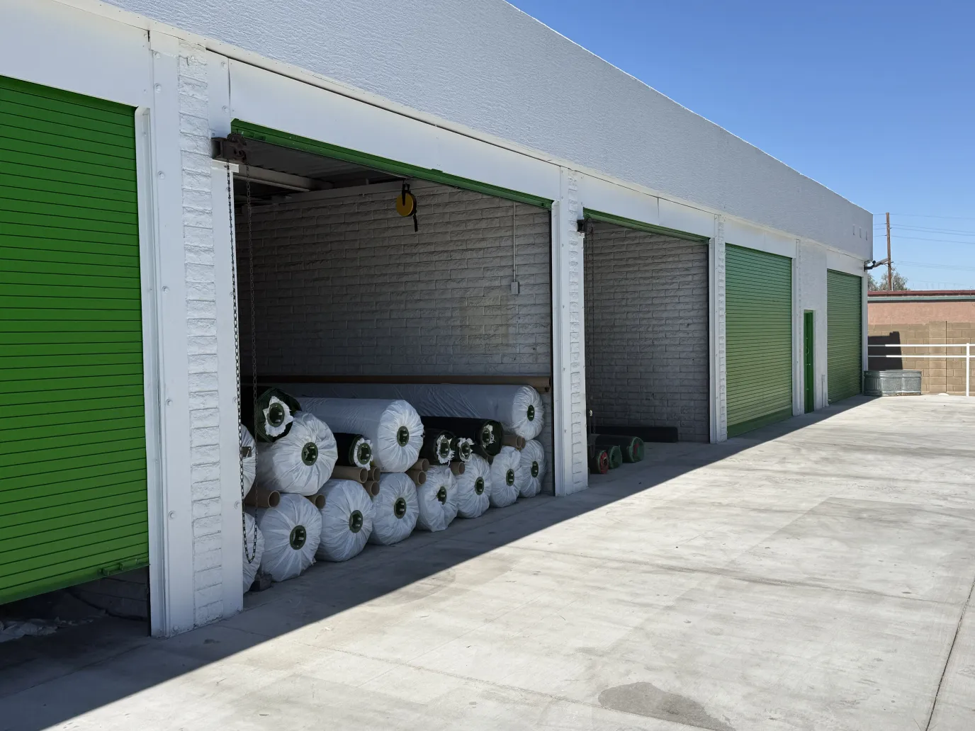 Bulk rolls of artificial turf stacked on pallets in a wholesale supply yard
