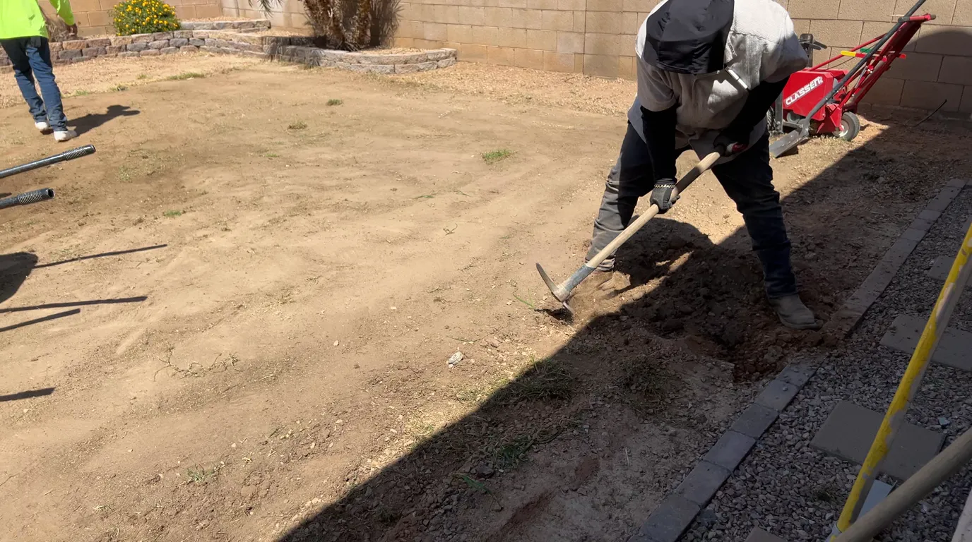 A crew member grading the base and shaping the drainage slope with a rake