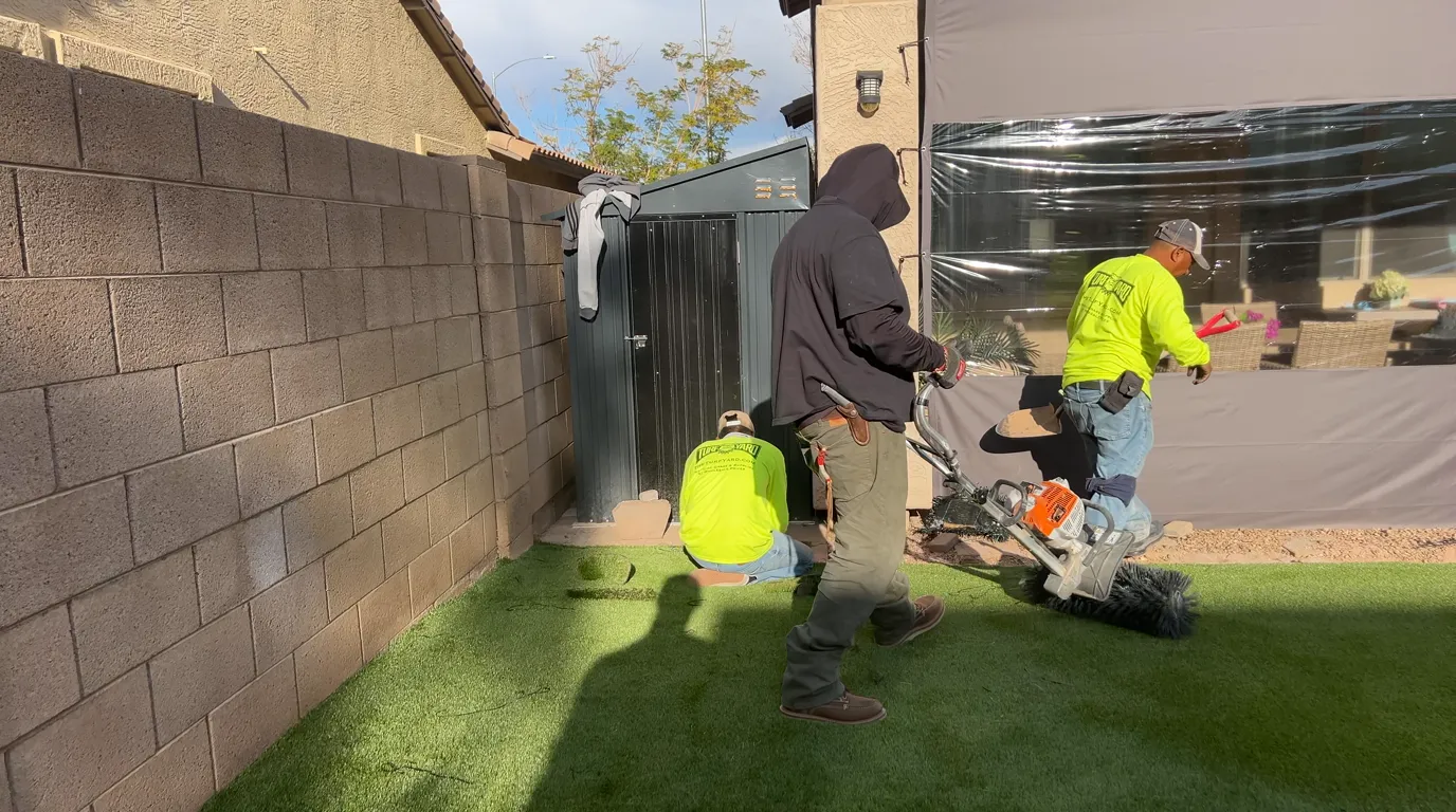 Power-brooming infill into the finished green artificial turf along a wall