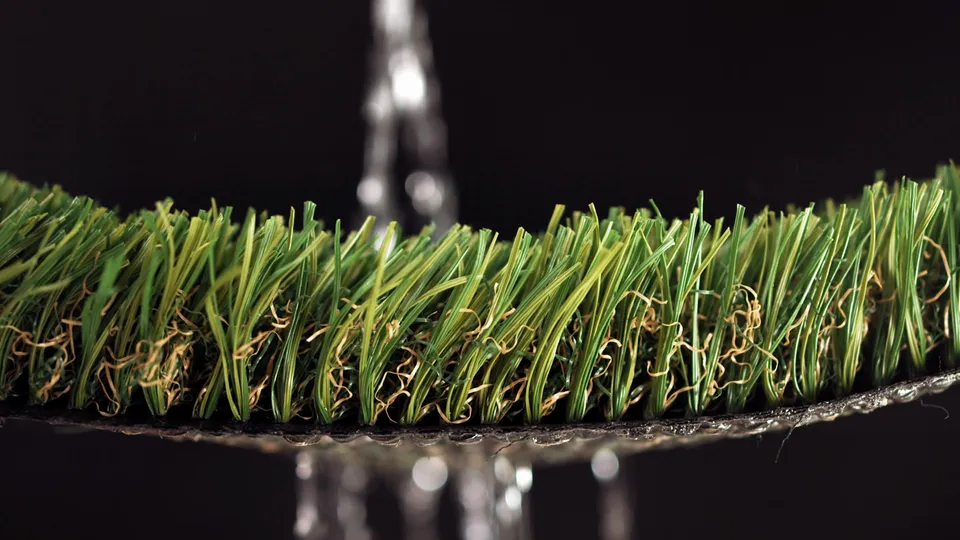 Water draining freely through an artificial turf cross-section, showing the breathable layers below